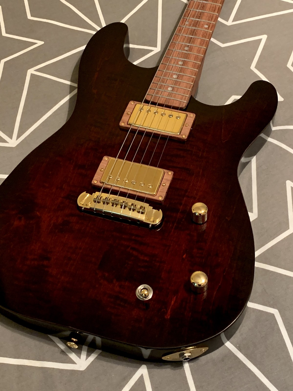 Completed guitar close-up showing strings, gold pickups and red wood grain