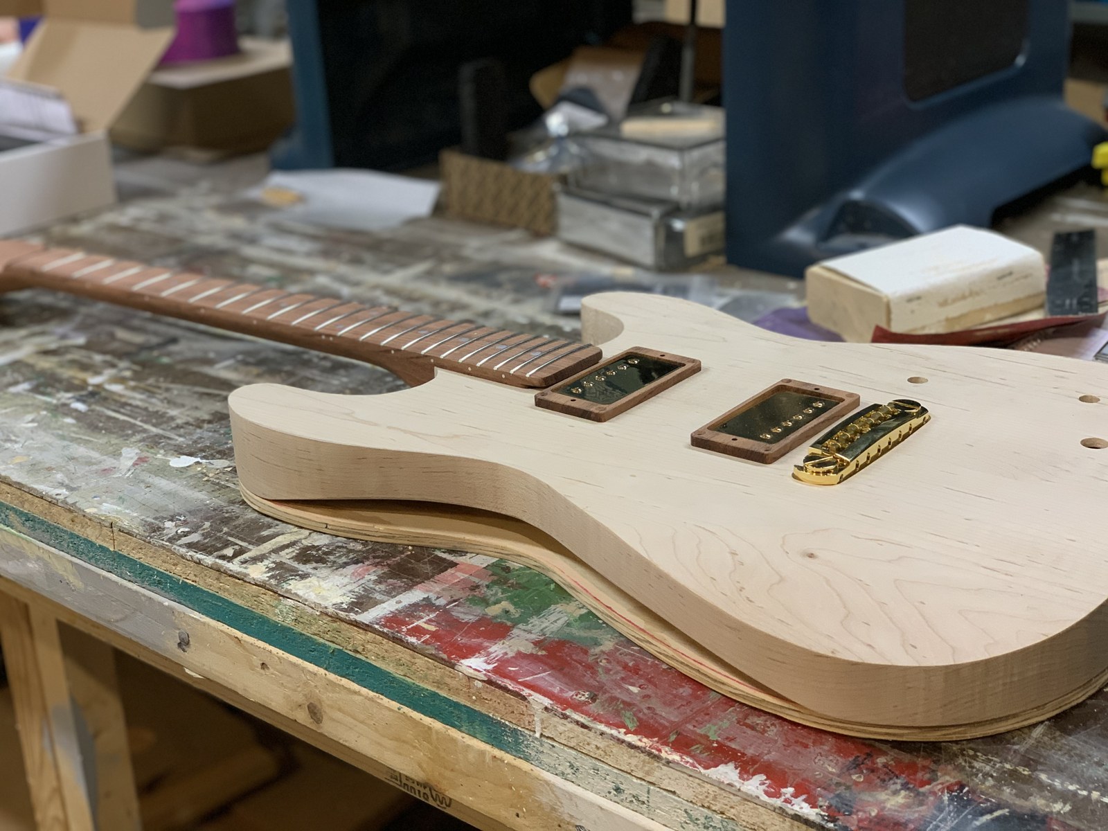 Bare guitar with neck, gold pickups and bridge test fitted on a workbench