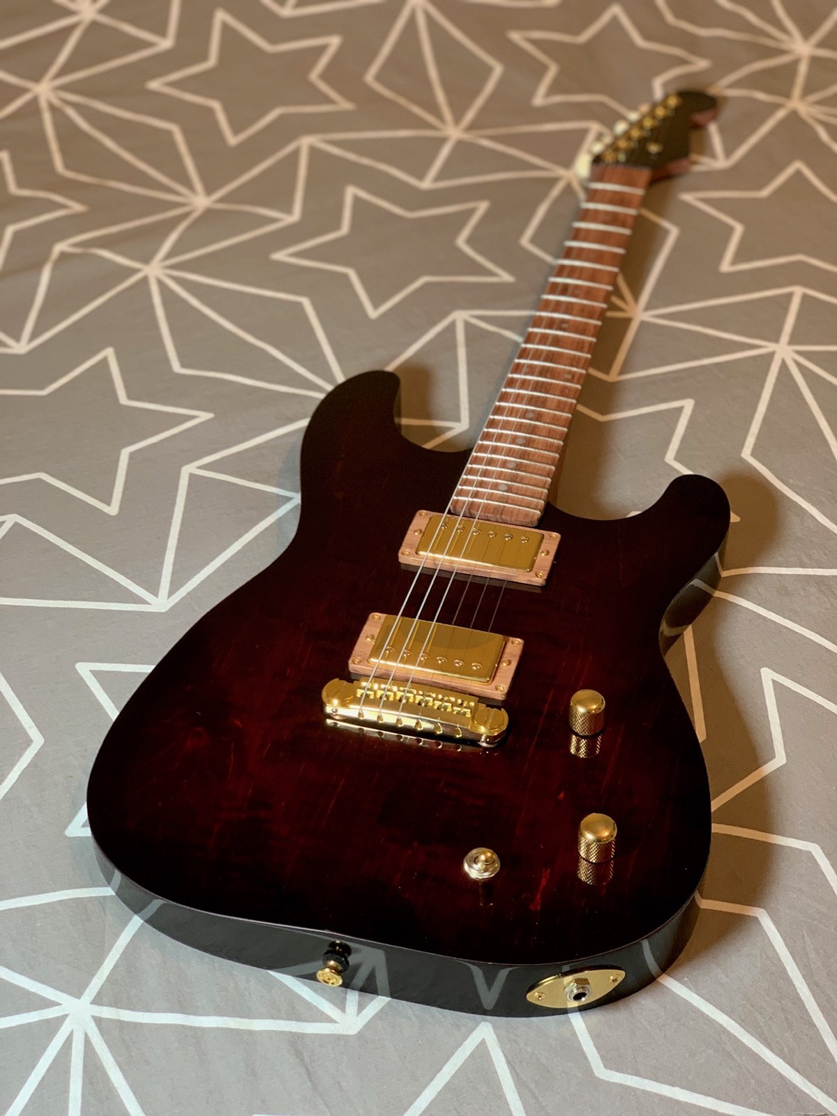 Completed red S-style guitar with gold humbuckers, bridge and controls