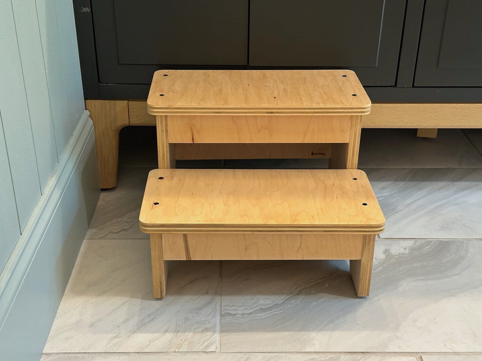 Front view of the completed two-step stool showing both wooden treads and the open space between them